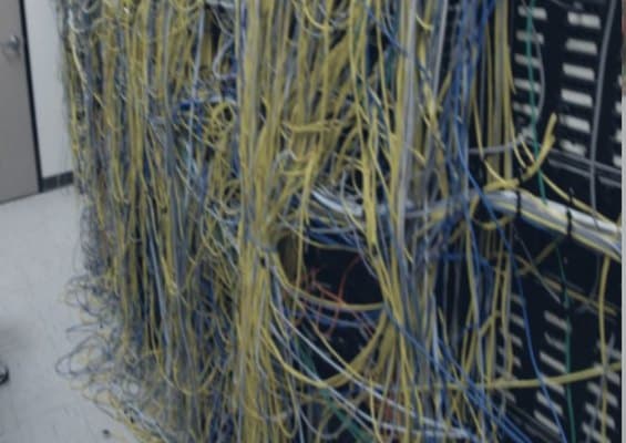 Dense, tangled legacy network cabling on a rack before the refresh